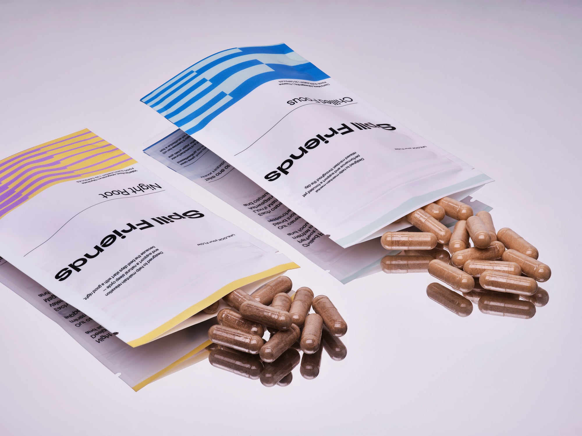 Night Root and Chilled Focus pouches – Spill Friends sleep and focus supplements with capsules on light mauve surface
